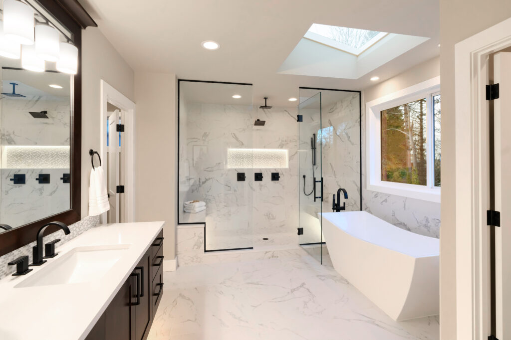 A modern bathroom with marble finish, double vanity, freestanding tub, and glass shower, highlighting the trend in Marlboro home upgrades.